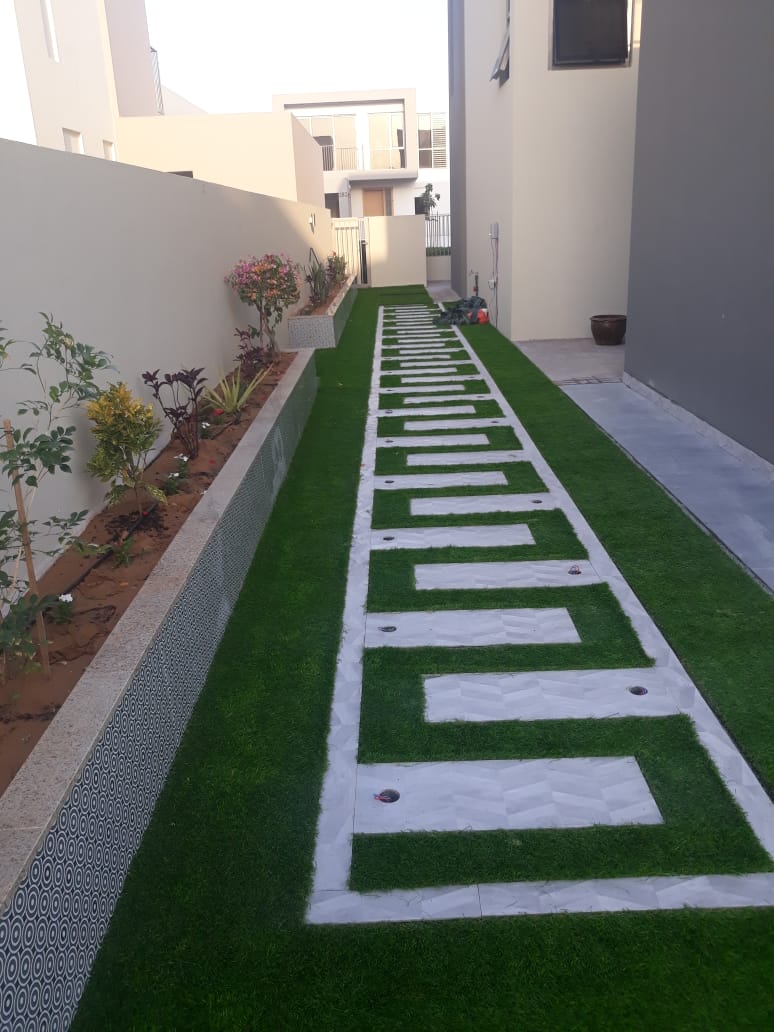 Geometric lawn and stone steppers — Damac Hills side yard, by Blue Iconic